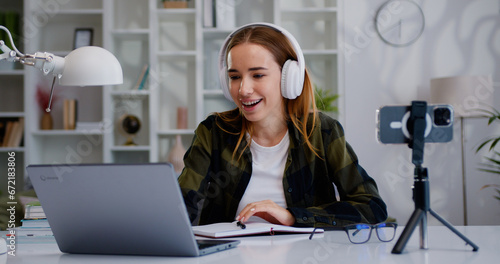 Smiling girl social media channel blogger content creator recording vlog video tutorial on smartphone camera in ligh troom. photo