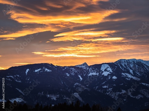 Beautiful dramatic orange golden sunset over a snowy winter mountain ridge © MatyasSipos