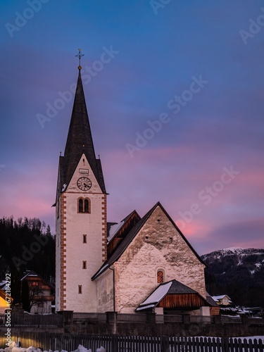 Village church in the mountains, winter christmas landscape, snow mountains, sunset, colorful sky