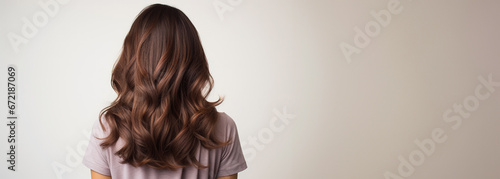 Backside portrait of a woman with stylish brown hair against a white backdrop. Hair dresser concept.