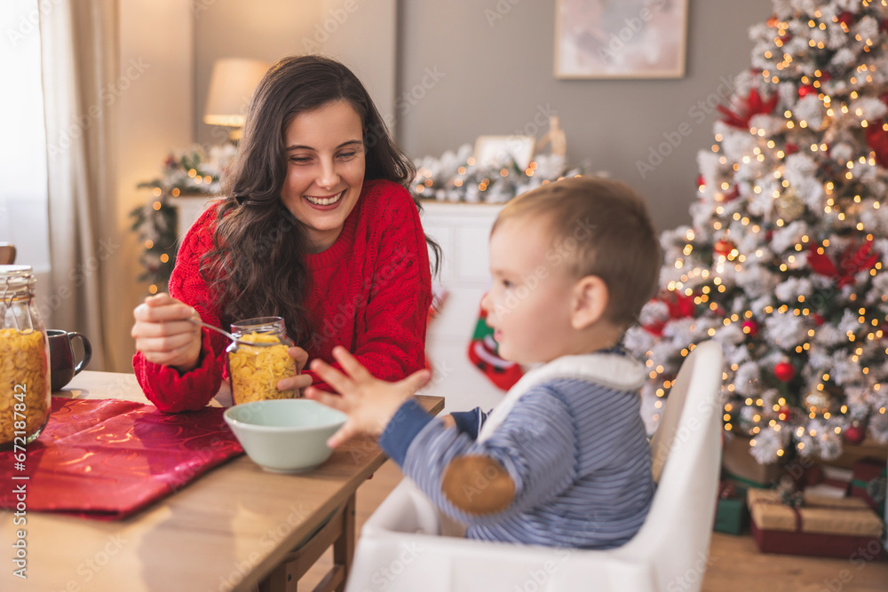 Mother feeding baby by the Christmas tree Mother feeding baby by the Christmas tree