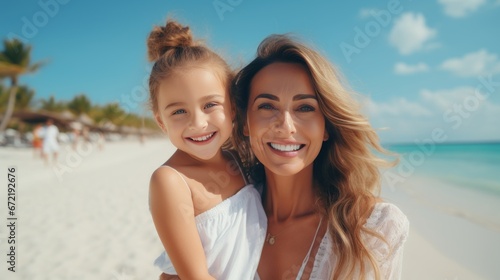 Mom and daughter on the azure beach in white clothes. © OLGA RA