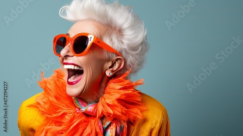 Happy senior woman in colorful orange outfit, cool sunglasses, laughing and having fun in fashion studio