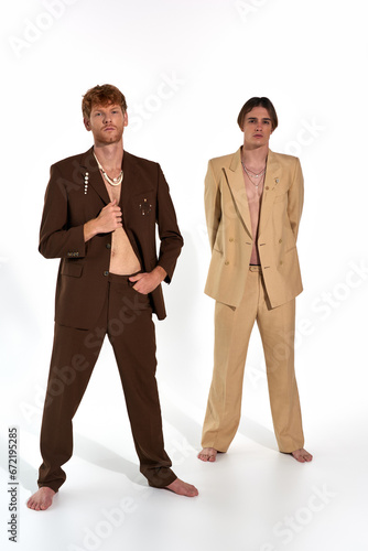 vertical shot of attractive male models in classy suits standing and looking at camera, men power