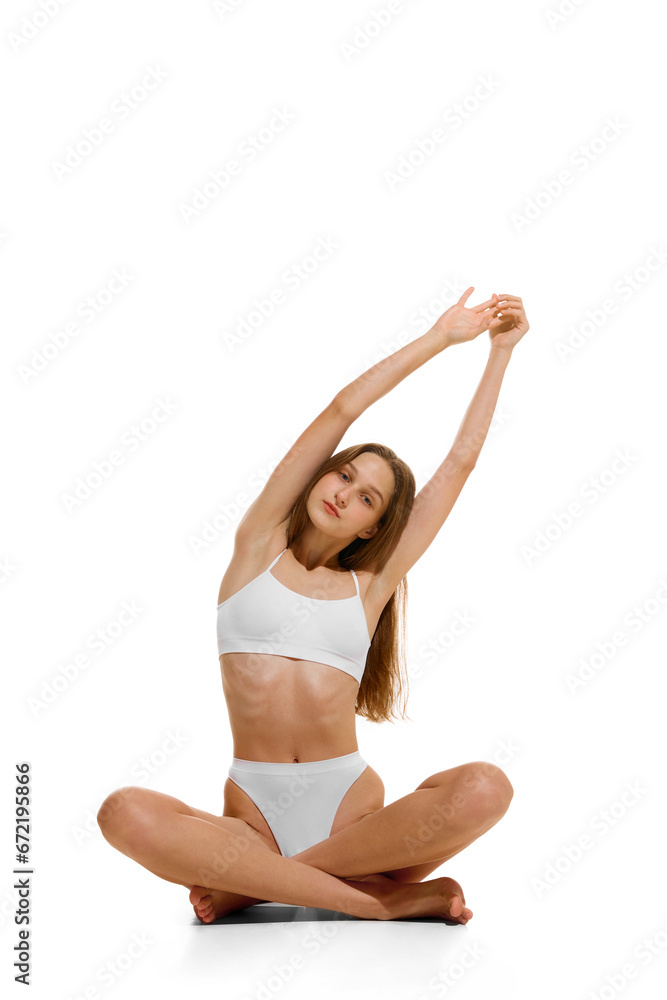 Smiling beautiful naked girl dressed in lingerie sitting in lotus pose on floor and doing exercises for back raised, starching hands up. Concept of recreation. Smiling beautiful naked girl dressed in lingerie sitting in lotus pose on floor and doing exercises for back raised, starching hands up. Concept of recreation.