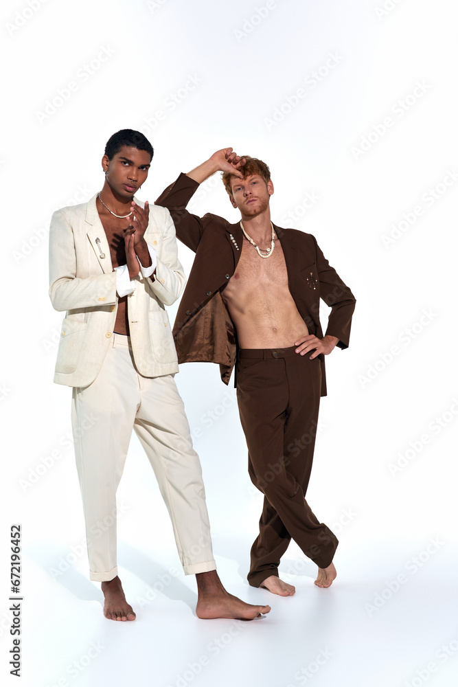 vertical shot of multiethnic sexy men posing barefoot in suits on white backdrop, fashion concept vertical shot of multiethnic sexy men posing barefoot in suits on white backdrop, fashion concept