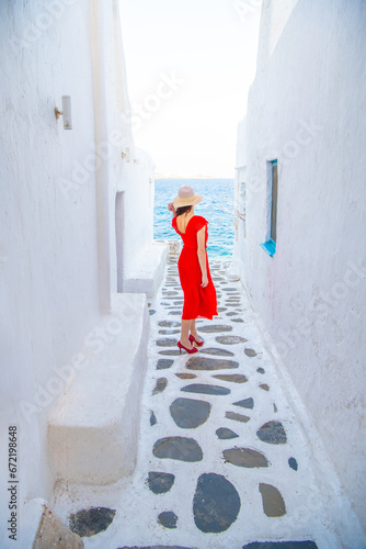 Woman in red dress at the Streets of old town Mykonos during a vacation in Greece, Little Venice Mykonos Greece © Kyrenian