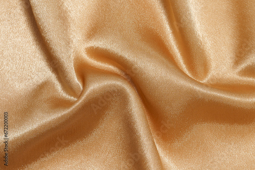 texture of crumpled wrinkled shiny beige synthetic or polyester fabric close-up. Fabric for sewing festive costumes, clothes. Elegant background for your design