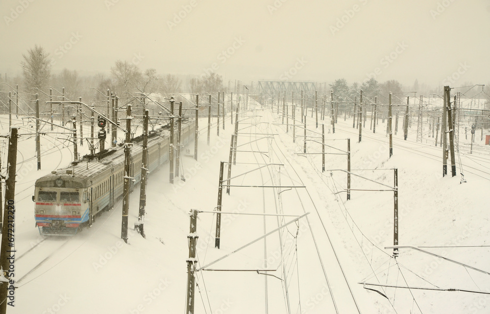A long train of passenger cars is moving along the railway track. Railway landscape in winter after snowfall A long train of passenger cars is moving along the railway track. Railway landscape in winter after snowfall
