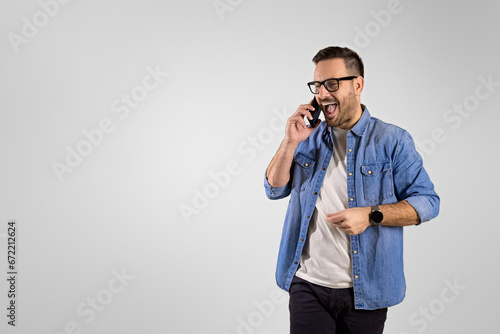 Businessman screaming ecstatically while listening good news over mobile phone on white background © Moon Safari