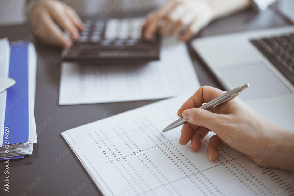 Woman accountant using a calculator and laptop computer while counting taxes for a client. Business audit concepts Woman accountant using a calculator and laptop computer while counting taxes for a client. Business audit concepts