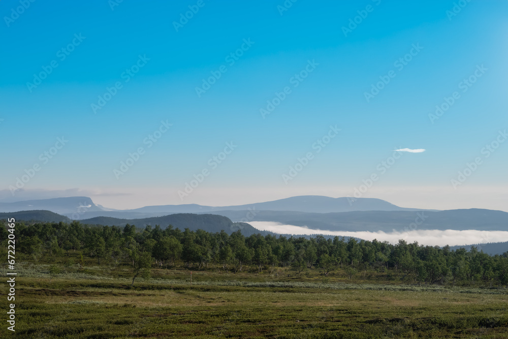 Early in the morning up in the mountains of Tänndalen in Sweden. A beautiful blue sky and morning mist still lingering down in the valley.