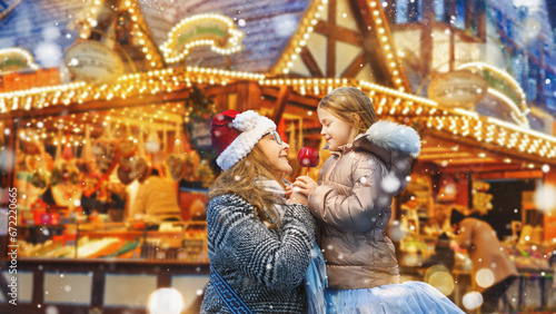 Happy mother and daughter eat a red sugar apple at the traditional German Christmas market. © Igor Link