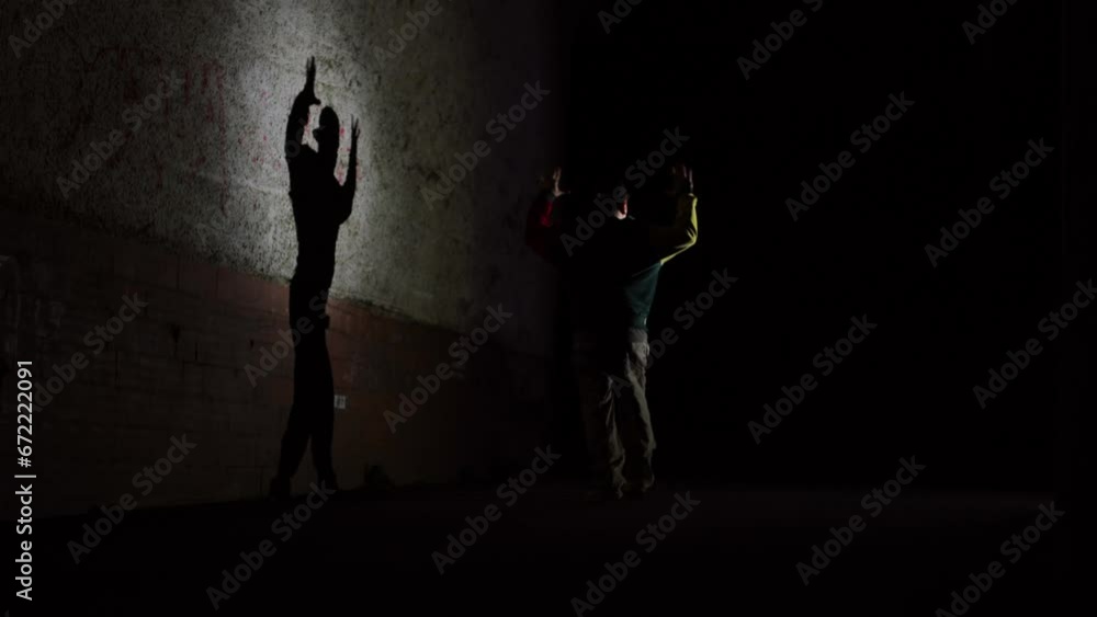 Hip hop dancing silhouette. Dance in the dark, a boy dances at night. Man makes dynamic movements, modern style. The light from the flashlight, he dances in the city near the house Hip hop dancing silhouette. Dance in the dark, a boy dances at night. Man makes dynamic movements, modern style. The light from the flashlight, he dances in the city near the house