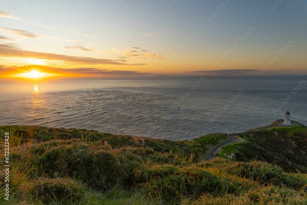 Scenic view of a lighthouse situated near the coastline of the ocean at sunset.