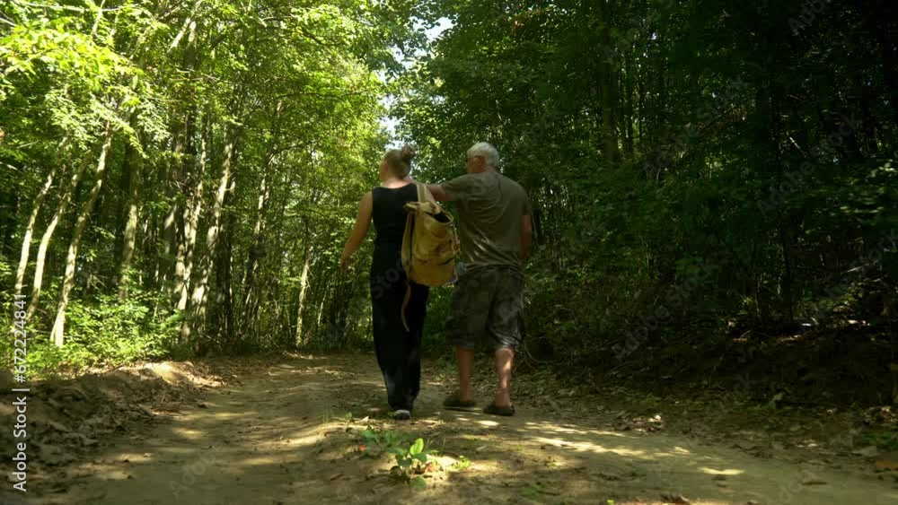 Couple walk on woodland track point at nature in dappled yellow sunlight Couple walk on woodland track point at nature in dappled yellow sunlight
