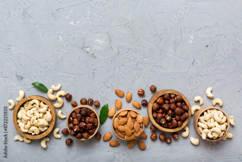 Assortment of nuts in wooden bowl on colored table. Cashew, hazelnuts, walnuts, almonds. Mix of nuts Top view with copy space