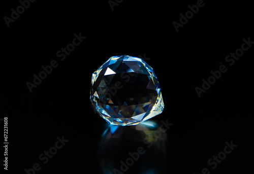 A close-up with a precious stone shining on a black background. A large isolated diamond illuminated in the dark