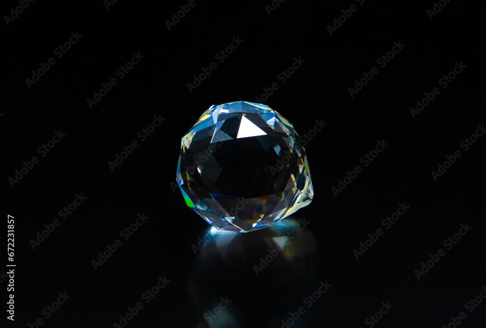 Fototapeta premium A gemstone crystal sparkling on a dark background. Diamond imitation on a black background