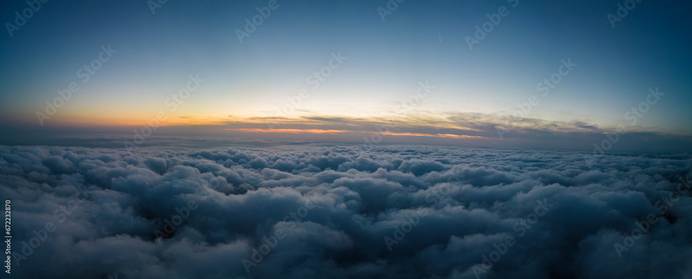 A drone flies over fluffy clouds at sunset. The drone flies through the clouds, creating a sense of wonder and awe