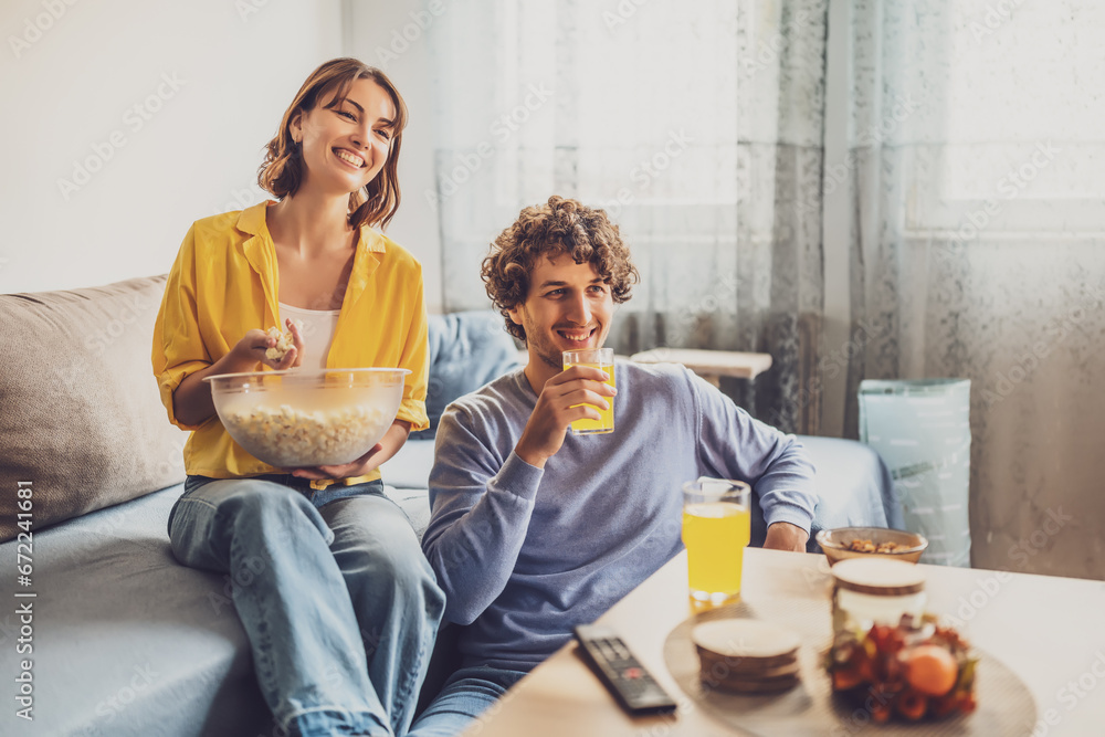 Portrait of young happy couple who is relaxing and watching TV at home. Portrait of young happy couple who is relaxing and watching TV at home.