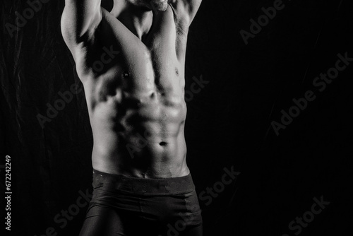 Confident, attractive shirtless muscular young man topless in studio