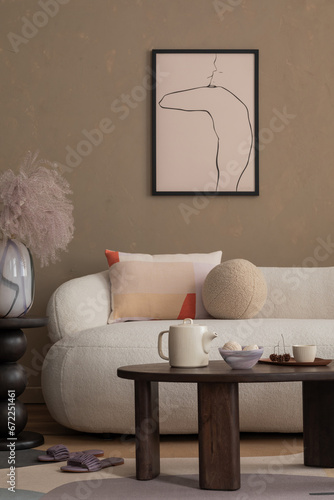 Stylish composition of warm living room interior with mock up poster frame, boucle sofa, wooden coffee table, pillows, pitcher, brown wall and personal accessories. Home decor. Template.
