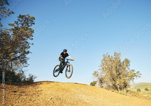 Downhill, mountain bike and man outdoor in nature for extreme sports, training or workout. Hill, countryside and male person with courage or bicycle stunt for off road cycling, travel or adventure