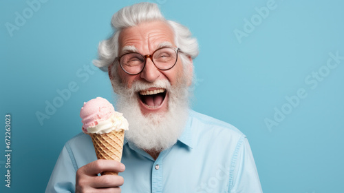 Happy senior man eating ice cream at blue background photo