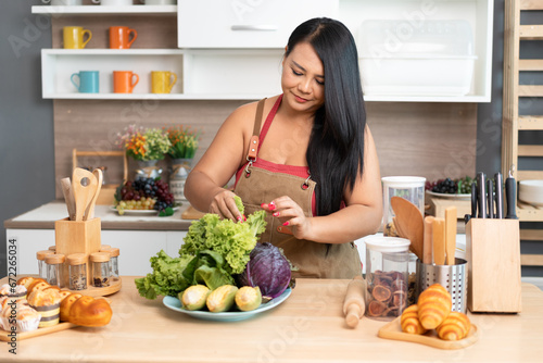 Happy Asia plus size woman prepare cooking vegetables salad in kitchen at home 