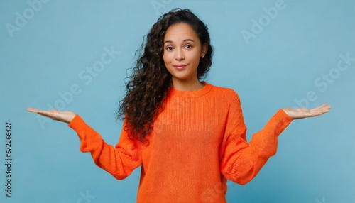 Young confused puzzled latin professional woman, doubtful uncertain hispanic female model student wearing orange sweater standing shrugging thinking of difficult choice isolated  photo