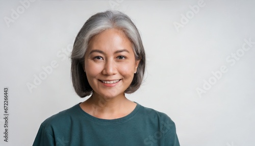 Mature beautiful middle aged asian woman, senior older grey haired lady looking at camera touching face applying under eye antiaging anti wrinkle perfect skin care cream, isolated on white headshot photo