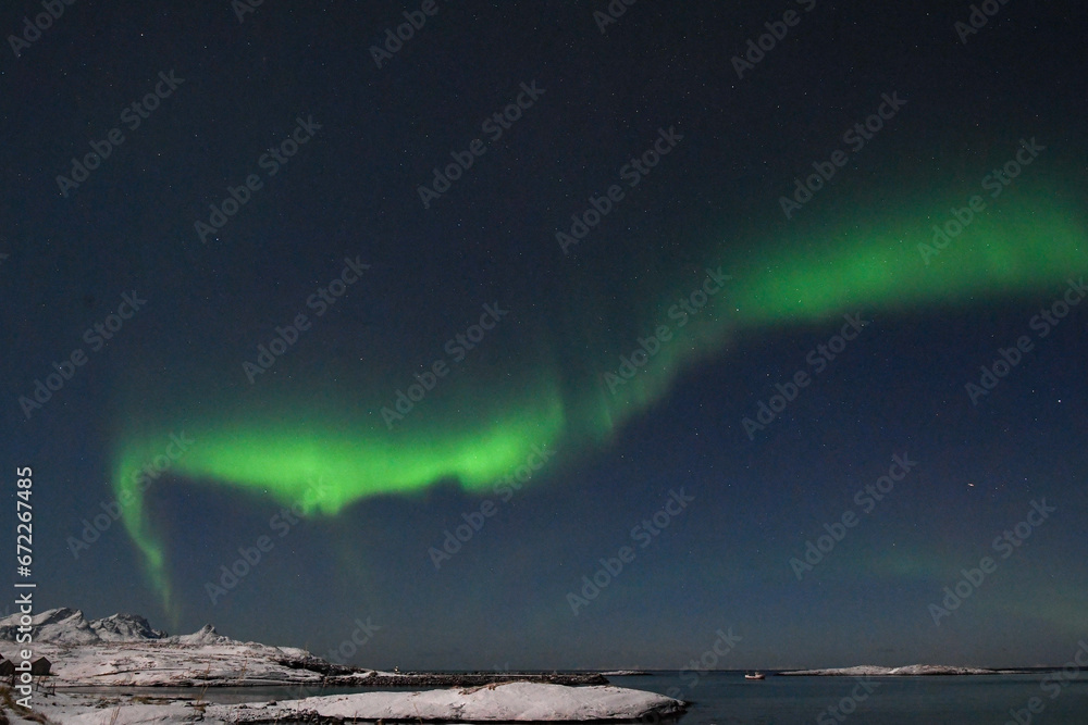 Bright Green Colours of the Northern Light, Aurora Borealis illuminate the Night Sky over the beach at Mjelle, in Arctic Norway.