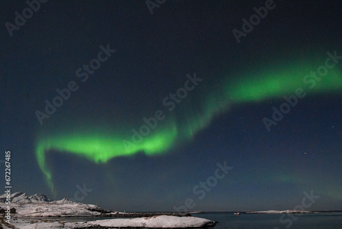 Bright Green Colours of the Northern Light  Aurora Borealis illuminate the Night Sky over the beach at Mjelle  in Arctic Norway.