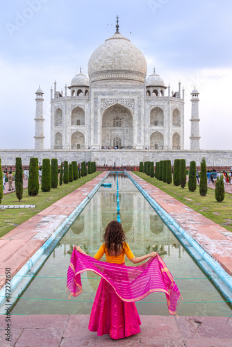 Woman looks at the imposing Taj Mahal in Agra, India, with its wonderful architecture on a cloudy day