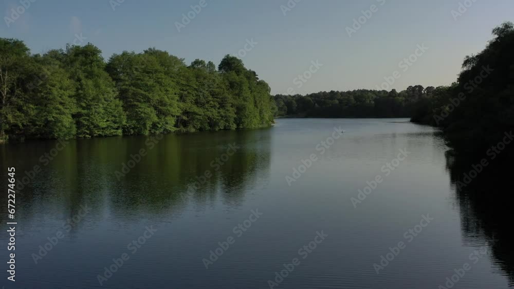 Calm drone scene of a reflecting pond with trees with blue sky at sunset Calm drone scene of a reflecting pond with trees with blue sky at sunset