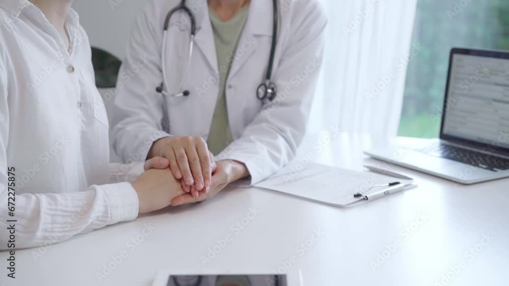 Doctor and patient sitting at the white table in the hospital. The pediatrician in a green blouse and white medical coat is reassuring a woman. Empathy in Medicine and Healthcare Doctor and patient sitting at the white table in the hospital. The pediatrician in a green blouse and white medical coat is reassuring a woman. Empathy in Medicine and Healthcare