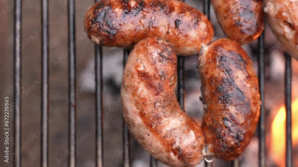 Overhead flat lay closeup shot of delicious sizzling scorched sausages on the grill during a BBQ barbecue outdoors. Overhead flat lay closeup shot of delicious sizzling scorched sausages on the grill during a BBQ barbecue outdoors.