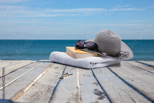 Buch, Handtuch, sonnenbrille  und Sonnenhut am Strand