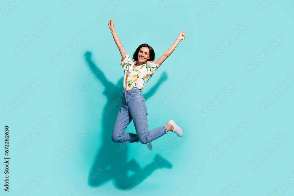 Obraz premium Full length photo of carefree cheerful girl wear trendy outfit raise fist yes hooray good mood isolated on bright cyan color background
