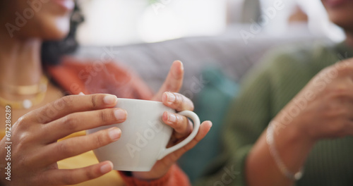Lgbtq couple, coffee and women on sofa in home for bonding, connection and relax together. Love, lesbian date and hands of people drinking tea in living room for chatting, social visit and talking photo