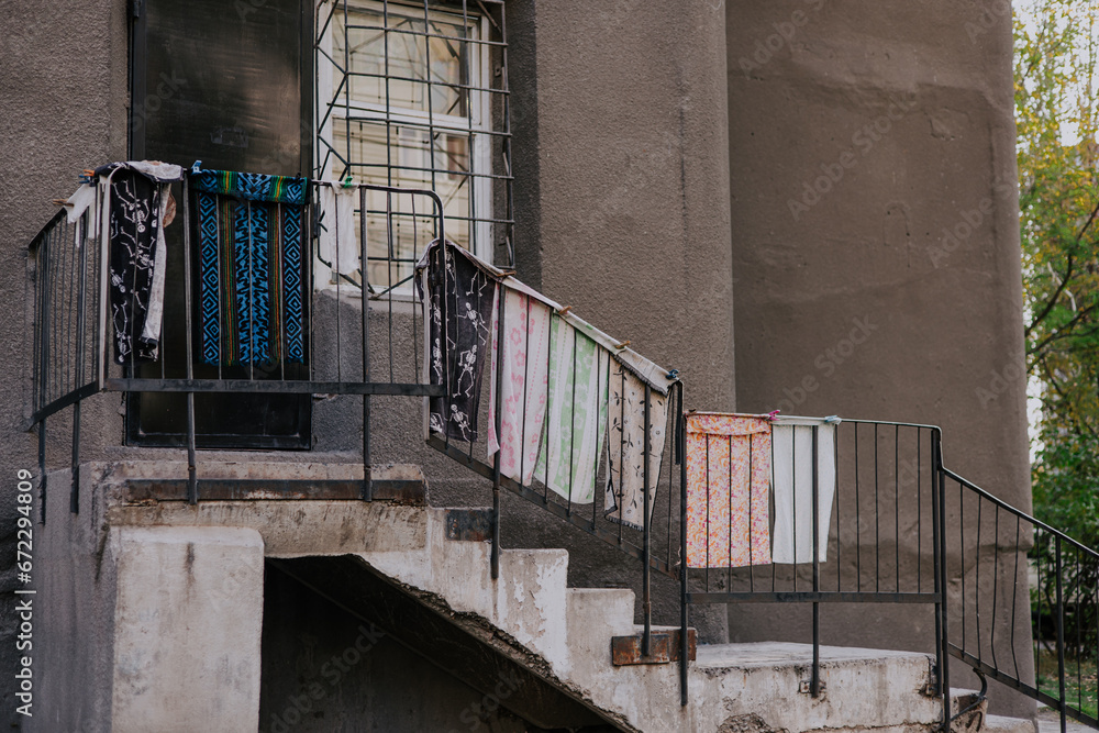 Lack of space in living quarters. Towels drying outside, hanging on the staircase railing, near the door, entrance to the room. Courtyard of a residential building in the CIS countries. Lack of space in living quarters. Towels drying outside, hanging on the staircase railing, near the door, entrance to the room. Courtyard of a residential building in the CIS countries.