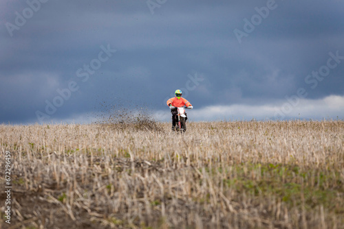 motocross dirtbike rider in field in front of dark blue sky
