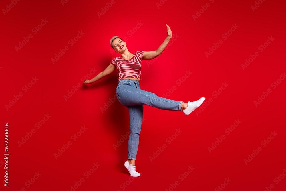 Full length photo of cheerful lovely girl wear stylish clothes have fun enjoying summer vacation walk isolated on red color background