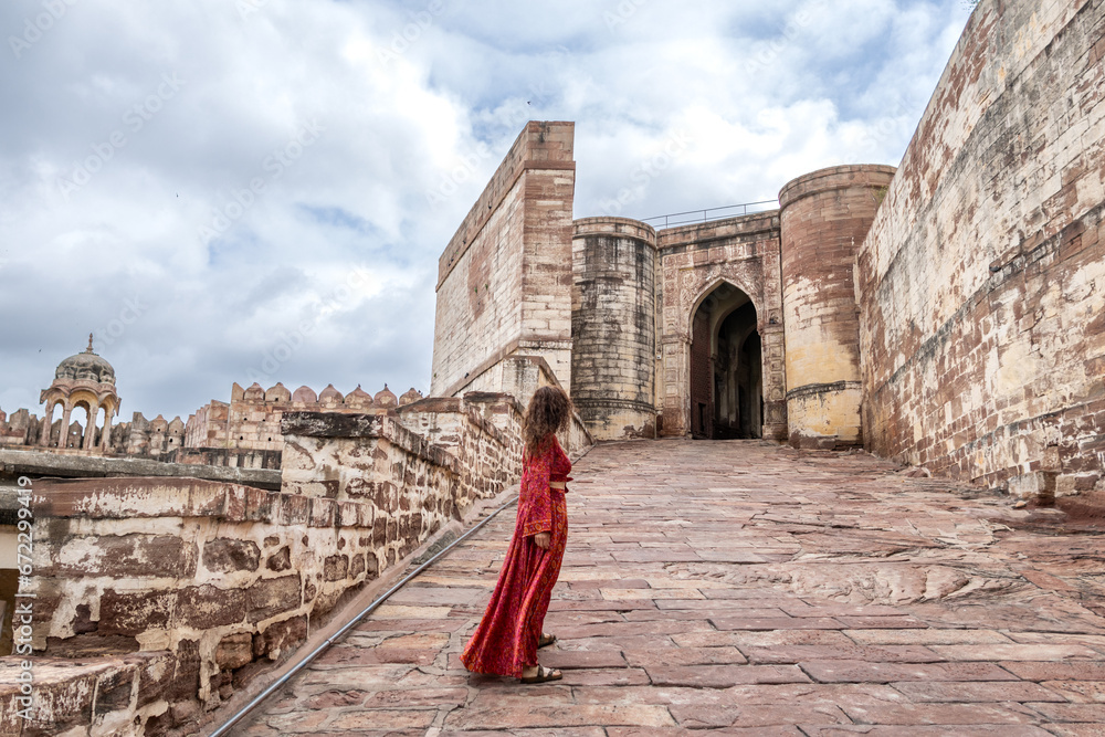 Woman dressed in red walking through Mehrangarh Fort in Jodhpur in Rajasthan, India. Known as the blue city