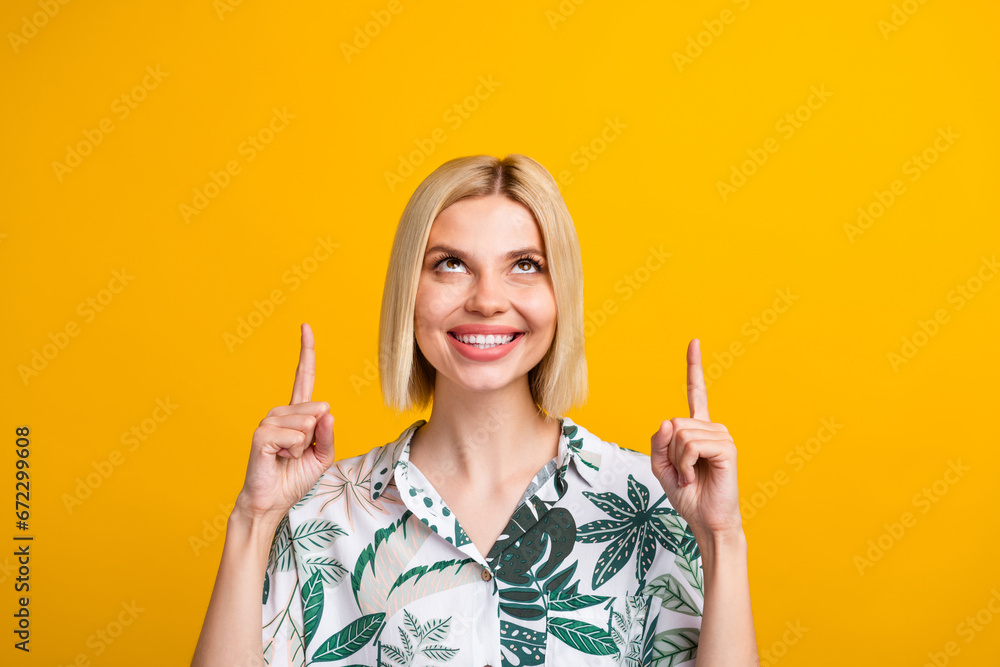 Photo portrait of pretty young girl point look up empty space promoting wear trendy leaves print outfit isolated on yellow color background Photo portrait of pretty young girl point look up empty space promoting wear trendy leaves print outfit isolated on yellow color background