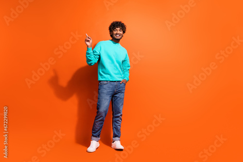 Full length portrait of nice handsome man indicate finger empty space novelty isolated on orange color background