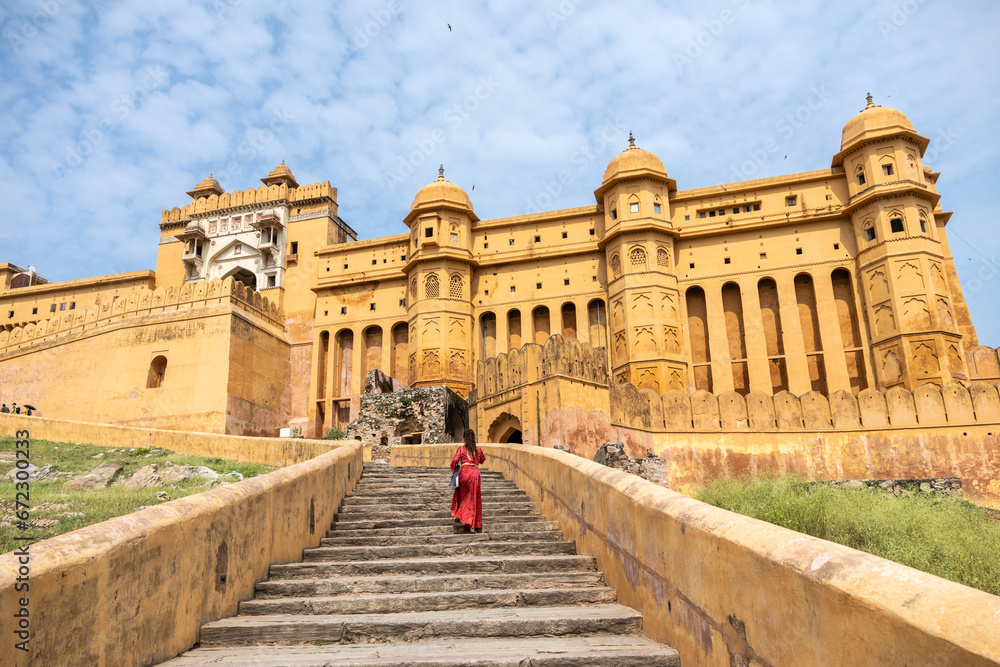 Woman at the entrance to Amber Fort in daytime with cloudy sky, near Jaipur, The Pink City, Rajasthan, India