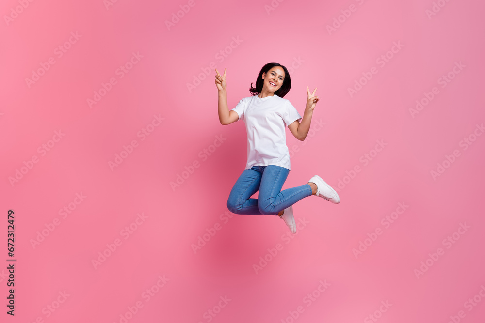Full length photo of funky active woman jumping trampoline showing double v sign at black friday promo ad isolated on pink color background