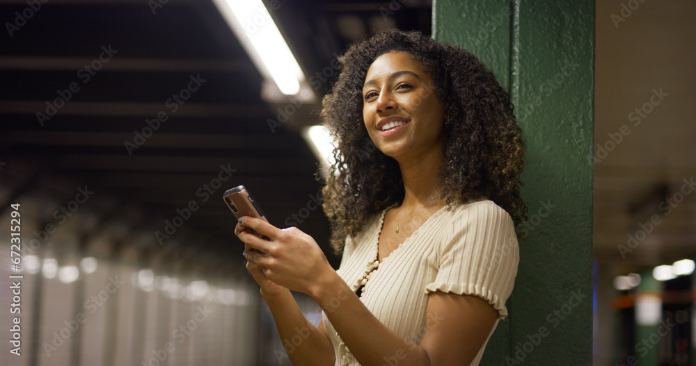 Young black woman using smartphone at a subway platform Young black woman using smartphone at a subway platform
